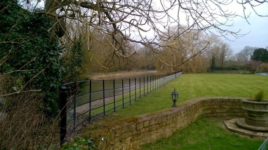 9b2c4b44fb86522964124ed80d03c5e8_XL Metal fencing forms a boundary between walled gardens and a river