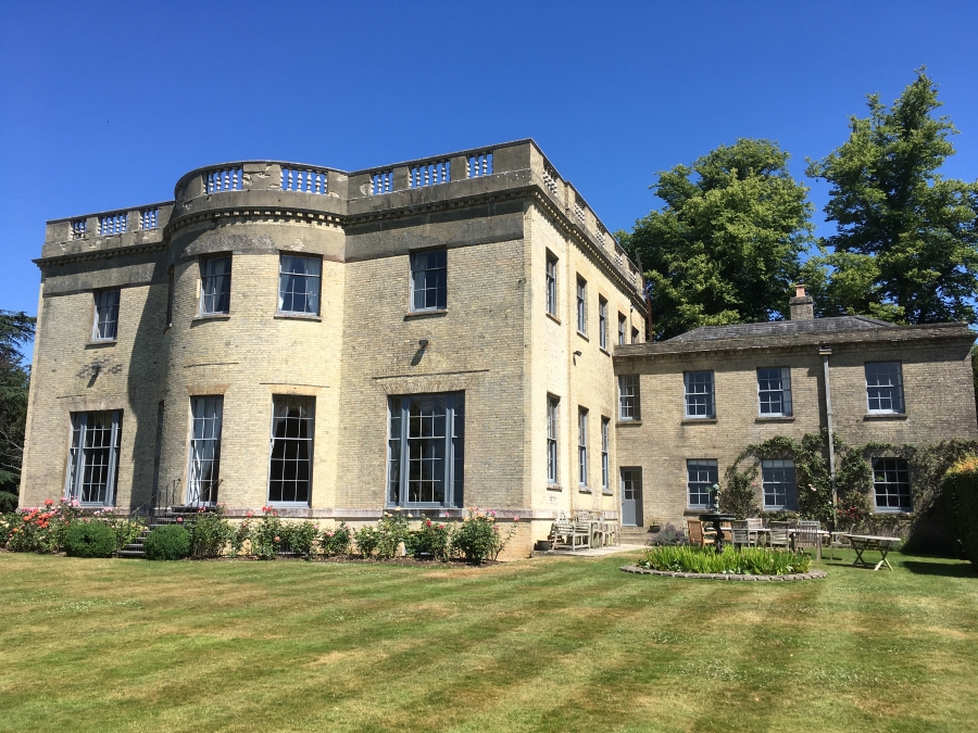 Pale brick build country property with lawned area and rose borders