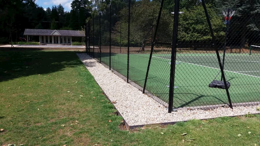 Tennis court surround from corner showing newly finished metal posts and gravel surround